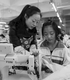 大英縣中等職業技術學校內，企業服裝技師正指導學生進行縫紉操作。